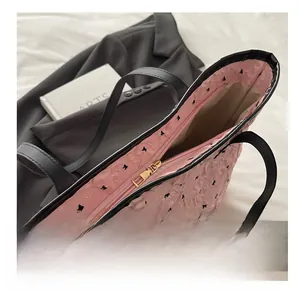 Close-up of smooth gold zipper on pink bubble tote bag with black bow print detail
