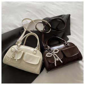 Detail of cream and brown Boston bags featuring pearl bow charms and flap pockets