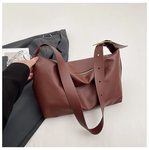 Detail view of burgundy leather tote bag with wide adjustable strap and metal hardware