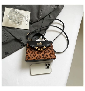 Detail of leopard print handbag featuring a black leather flap and gold turn-lock buckle
