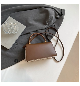 Detail view of a brown trapezoid handbag featuring vintage patterned leather patchwork