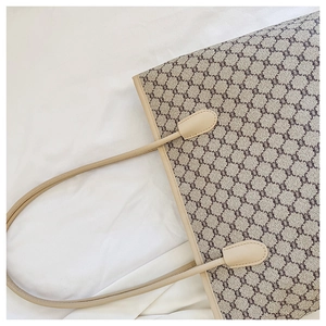 Close-up of monogram pattern tote bag with beige leather trim on white fabric