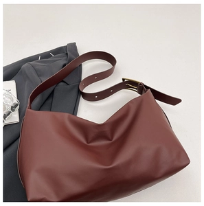Macro detail of dark brown leather shoulder bag with vintage brass buckle and wide strap