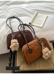 Draufsicht auf zwei Wildleder-Boston-Taschen in Braun mit Plüsch-Hundeanhängern