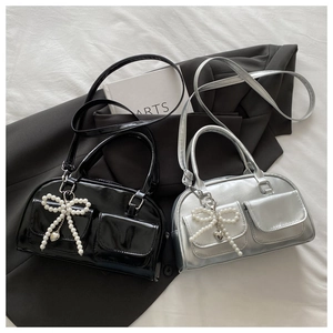 Detail of chic Boston bag featuring Y2K pearl bow charm and metallic heart pendant