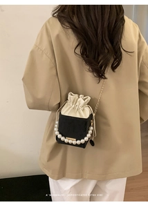 Rear view of a model wearing a black pearl handle mini bag with chain strap