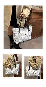 Detailed view of white tote bag featuring black bow patterns and textured fabric finish