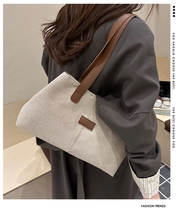 Minimalist beige canvas tote bag with brown leather shoulder strap on a model shoulder