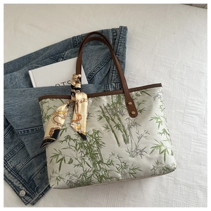 Detail view of tote bag with bamboo leaf print, leather handles, and silk scarf