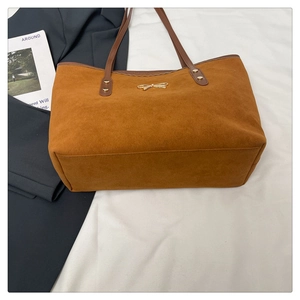 Detailed view of brown suede tote bag with golden bow hardware and leather straps