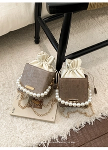 Detail of vintage bucket bag with pearl handle, chain strap, and drawstring closure