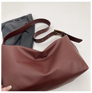 Detail of burgundy leather tote bag with adjustable wide strap and vintage gold buckle