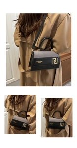 Detail of a two-tone crossbody bag featuring leather stitching and a metal buckle
