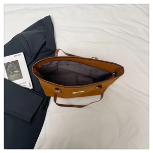 Macro view of a large brown tote bag interior with zipper pocket and metal bow detail