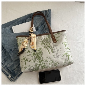 Close-up of bamboo embroidery on beige fabric tote bag with elegant silk scarf