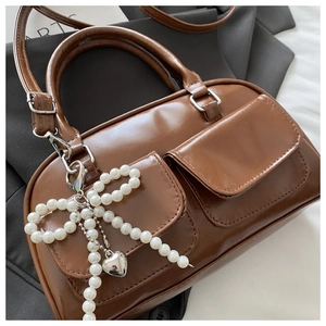 Detail shot of brown PU leather Boston bag featuring dual front pockets and pearl bow charm