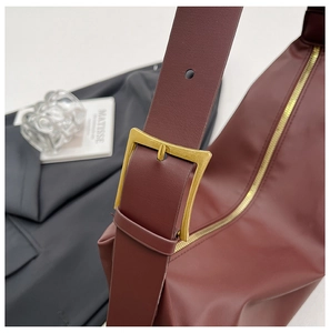 Macro detail of burgundy leather bag with oversized vintage gold buckle and metal zipper