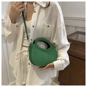 Detail of emerald green sequined crescent handbag with sparkling texture and handle