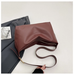 Detailed close-up of brown minimalist shoulder bag featuring zipper and adjustable strap