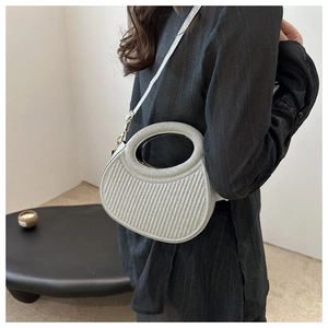 Detailed view of silver textured crossbody bag with unique cutout handle and chain strap