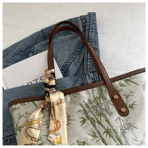 Close-up of bamboo print tote with brown leather handles and decorative silk scarf detail