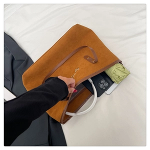 Macro view of large brown suede tote bag interior with umbrella and gold bow detail