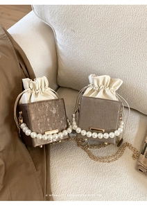 Detail of mini box bags with pearl handles and drawstring closure on beige fabric