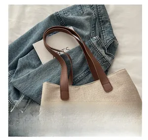 Detail of comfortable brown leather handles on off-white canvas tote bag for women