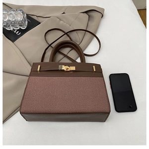 Détail du sac à main en cuir marron avec texture tressée et fermoir doré sur la table