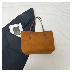 Close-up of brown suede tote bag with leather straps and golden rivet details