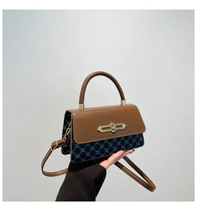 Detail of vintage navy pattern fabric with brown leather handle and gold metal clasp