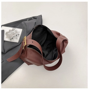 Detail view of red-brown leather shoulder bag showing black interior lining and gold buckle