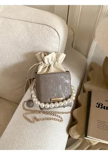 Detail of taupe mini drawstring bag with vertical textured leather and large pearl handle