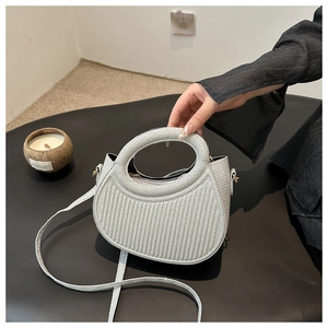 Detail of silver glitter half-moon handbag with hollow round handle and vertical texture