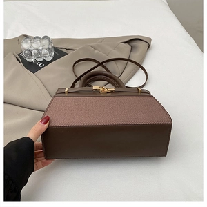 Détail du sac à main trapèze marron tendance avec finitions dorées sur fond blanc
