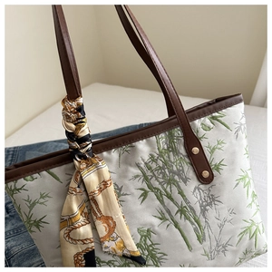 Detailed view of bamboo embroidery on tote bag with leather handles and silk scarf