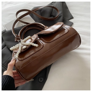 Brown faux leather Boston bag featuring double flap pockets and pearl bow charm detail