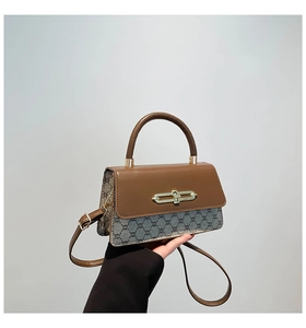 Close-up of vintage patchwork handbag with leather handle and gold metal clasp