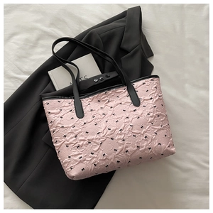 Close-up of pink pleated tote bag with black bow print and slim black shoulder straps