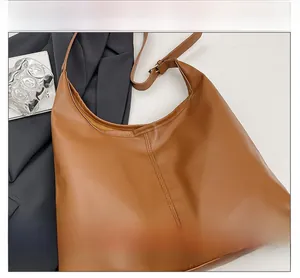 Close-up of brown PU leather hobo bag with vertical stitching and adjustable shoulder strap