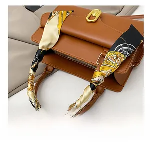 Close-up of a vintage printed silk scarf wrapped around a brown leather handbag handle
