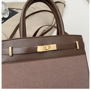 Détail du sac à main en cuir marron foncé et tissu sergé avec fermoir tournant doré