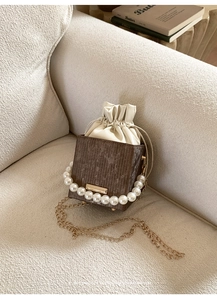 Detailed view of the luxury brown textured bucket bag featuring an elegant pearl handle