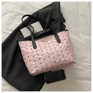 Detail view of pink polka dot tote bag with black bows on stylish black blazer