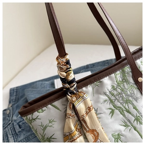 Detail of bamboo leaf print tote with leather handles and decorative silk scarf
