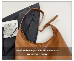 Detail view of the adjustable wide shoulder strap on a brown leather hobo bag