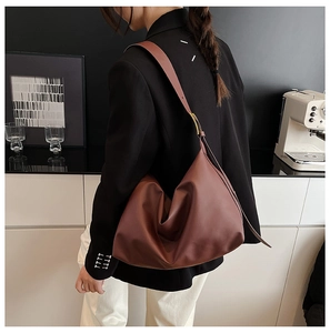 Detail view of large dark brown leather hobo bag with wide shoulder strap and gold buckle