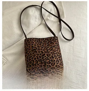 Detailed view of leopard print square bag showing compact size compared to a smartphone