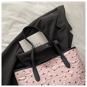 Detail of pink bubble texture tote bag with black bow print and leather handle