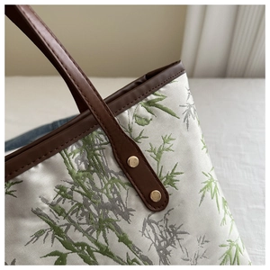 Detailed shot of bamboo jacquard fabric with brown leather handle and gold rivet studs